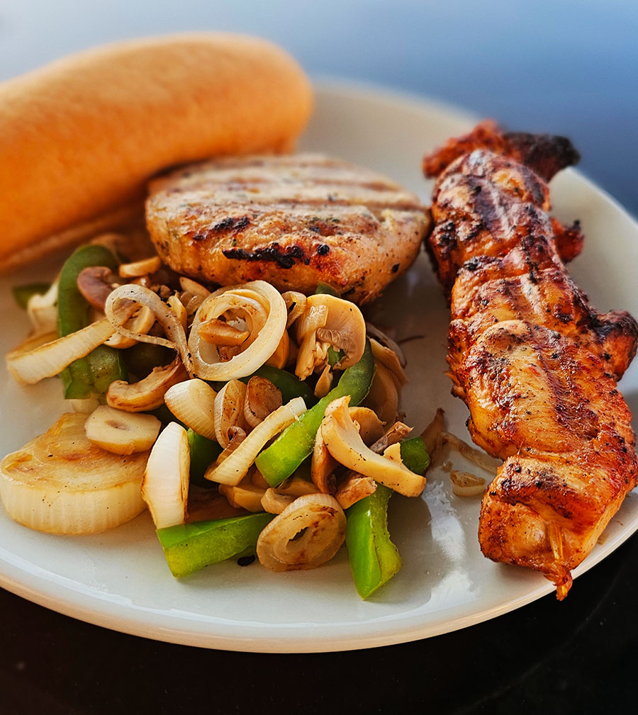 BBQ chicken and veg on a plate with a hot dog roll